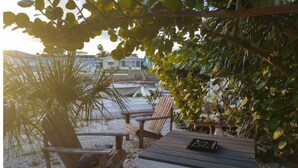 A wooden deck with a table and two chairs, surrounded by gravel and plants. - Casa Las Palmeras (Port Richey)