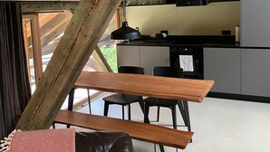 A rustic kitchen with wooden beams, a dining area with a bench, and a leather couch.