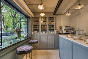 A kitchen with a window view, bar stools, and a countertop with kitchen appliances.