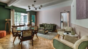 Una sala de estar con mesa de comedor de vidrio, sofá verde y una mesa de centro.