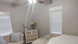 Une chambre à coucher avec un lit, une table de chevet, une lampe et un ventilateur de plafond.