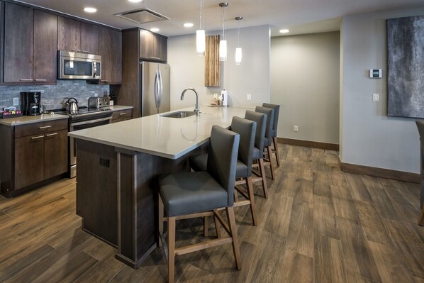 A modern kitchen with dark wood cabinets, stainless steel appliances, and a central island with bar stools.