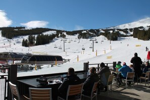 A ski resort with a dining area overlooking a snowy slope.