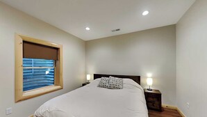 A bedroom with a bed, bedside lamps, a window with blinds, and a wooden floor. - Moon and Stars by Taylor Made Deep Creek (McHenry)