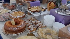 Un tavolo del buffet con diversi cibi, tra cui pasticcini, frutta e una torta.
