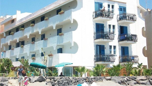 Un hotel a più piani con balconi, un muro in pietra e una bandiera.