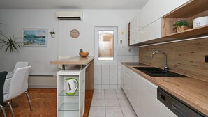 A modern kitchen with white cabinets, a wooden countertop, and a built-in dishwasher.