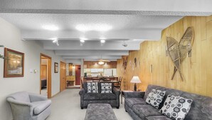 Ein Wohnzimmer mit grauen Sofas, einem grauen Sessel und einer Holzwand mit Schmetterlingsdekor.