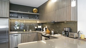 A modern kitchen with stainless steel appliances, a large island, and a dark wood backsplash. - Cozy Vail Retreat, On Shuttle Route, BBQ (Vail)