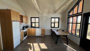A modern kitchen with wooden cabinets, a white refrigerator, a sink, and a dining table with chairs. - Minni-Borgir Cabins (Grímsnes- og Grafningshreppur)