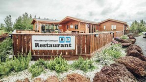 A wooden cabin-style building with a sign reading "Minniborgir Cottages Restaurant." - Minni-Borgir Cabins (Grímsnes- og Grafningshreppur)