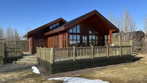 A wooden cabin with a deck, large windows, and a fenced area. - Minni-Borgir Cabins (Grímsnes- og Grafningshreppur)