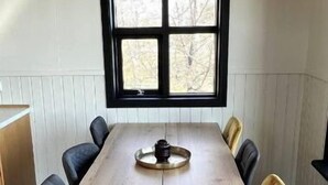 A rectangular dining table with a central decorative item, surrounded by chairs with black and yellow upholstery. - Minni-Borgir Cabins (Grímsnes- og Grafningshreppur)