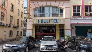 Un hôtel appelé Hollitel, avec une enseigne, de nombreuses fenêtres et des voitures garées devant.