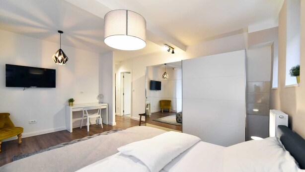A modern bedroom with a large bed, a desk, a chair, and a TV mounted on the wall. - Moin - Moin Apartment and Suite Zagreb (Zagreb)