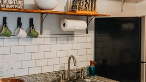 A kitchen with wooden cabinets, a granite countertop, a stainless steel sink, and a black refrigerator.