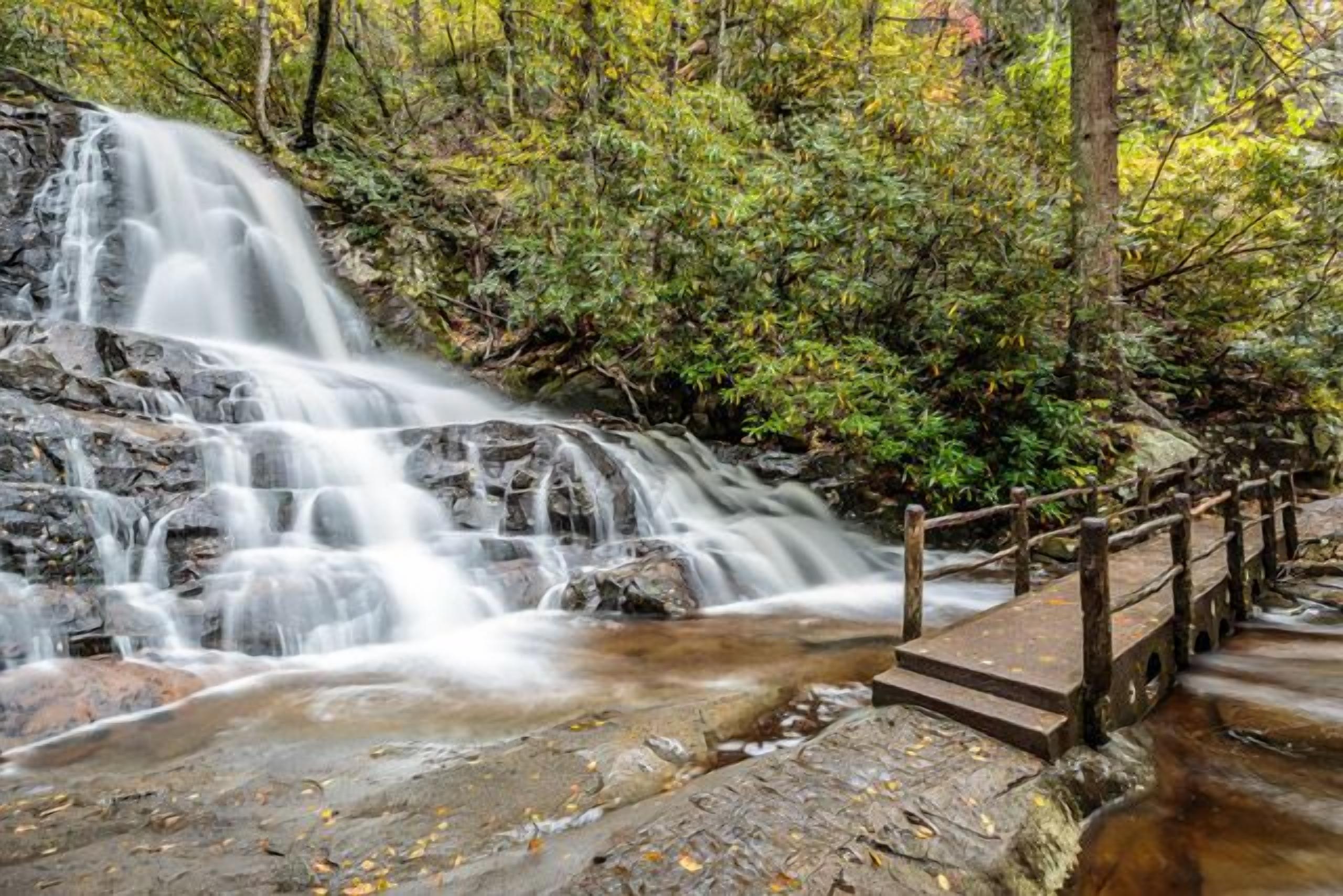 A waterfall with a wooden bridge leading over the water.