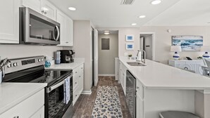 Una cocina moderna con armarios blancos, electrodomésticos de acero inoxidable y una isla central.