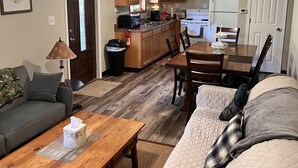 Un salón amplio con una mesa de centro de madera, un sofá color beige y una zona de comedor con una mesa y sillas de madera.