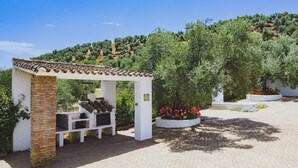 Un espacio de estar al aire libre cubierto, con un pilar de ladrillo, paredes blancas y techo de tejas.
