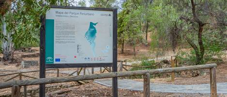 A signboard with a map and text, surrounded by trees and a wooden fence.