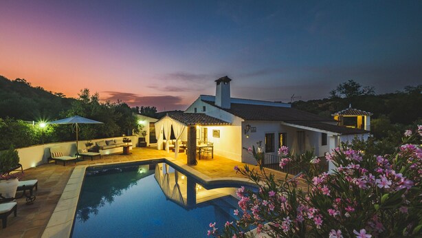 Un área de piscina con patio, un pabellón y una casa con techo de tejas.