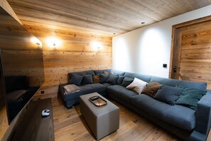 A modern living room with a wooden ceiling, a sectional sofa, a coffee table, and a TV.