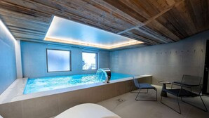 Une salle de spa moderne dotée d’un jacuzzi, de deux grandes fenêtres, d’une lucarne au plafond et d’un espace détente avec une table et des chaises.