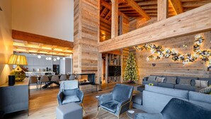 Un vaste espace de vie agrémenté d’une cheminée moderne, d’un coin repas et d’un sapin de Noël.