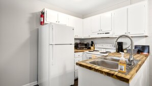 Une cuisine moderne avec des armoires blanches, un évier en acier inoxydable, un four à micro-ondes et un réfrigérateur.