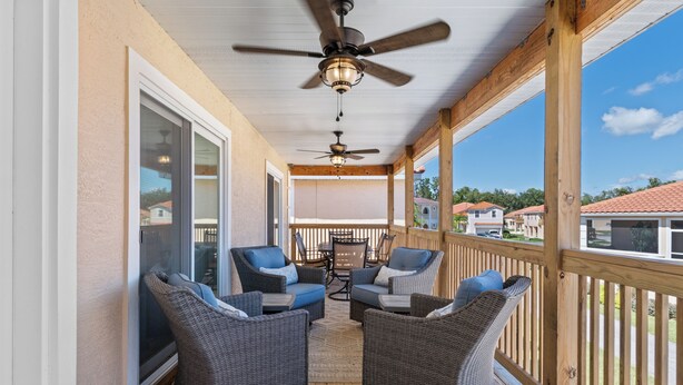 A covered outdoor area with wicker furniture, ceiling fans, and a view of the neighborhood. - Brand new August 2023 3 BR, 2 BA Tarpon on stilts (Homosassa)