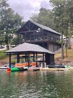 Situated over a serene body of water, this cabin offers a balcony with a view of the surrounding landscape and a covered dock for boats.