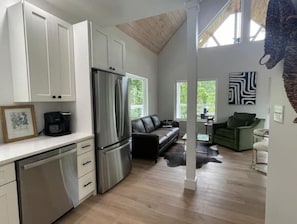 Cozy living space with a kitchenette, sofa, and dining area, featuring a sloped ceiling and exposed beams.