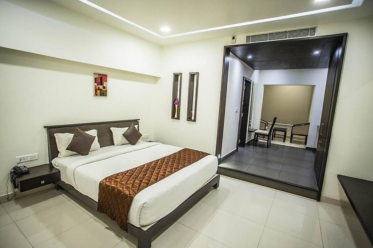 A modern hotel room with a large bed, a desk, and a view of the outdoor area.