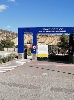 La entrada a Centre D'Estivage IMI Ouaddar, con un portón azul y un letrero en árabe.