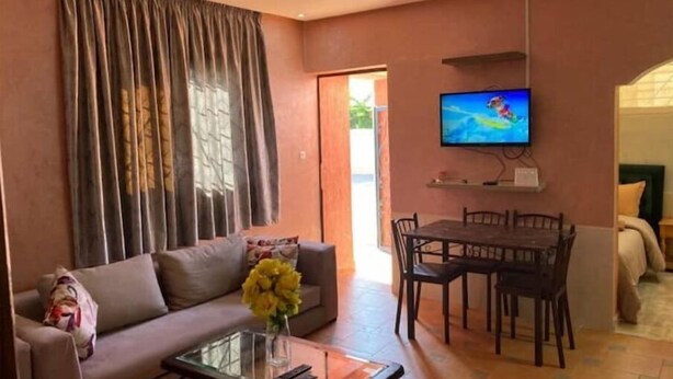 Una sala de estar con sofá, mesa de centro, televisor y comedor.