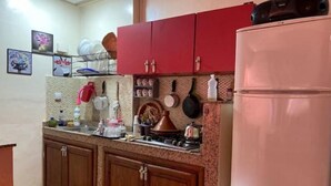 Una cocina con armarios de madera, una estufa y un refrigerador rosa grande.