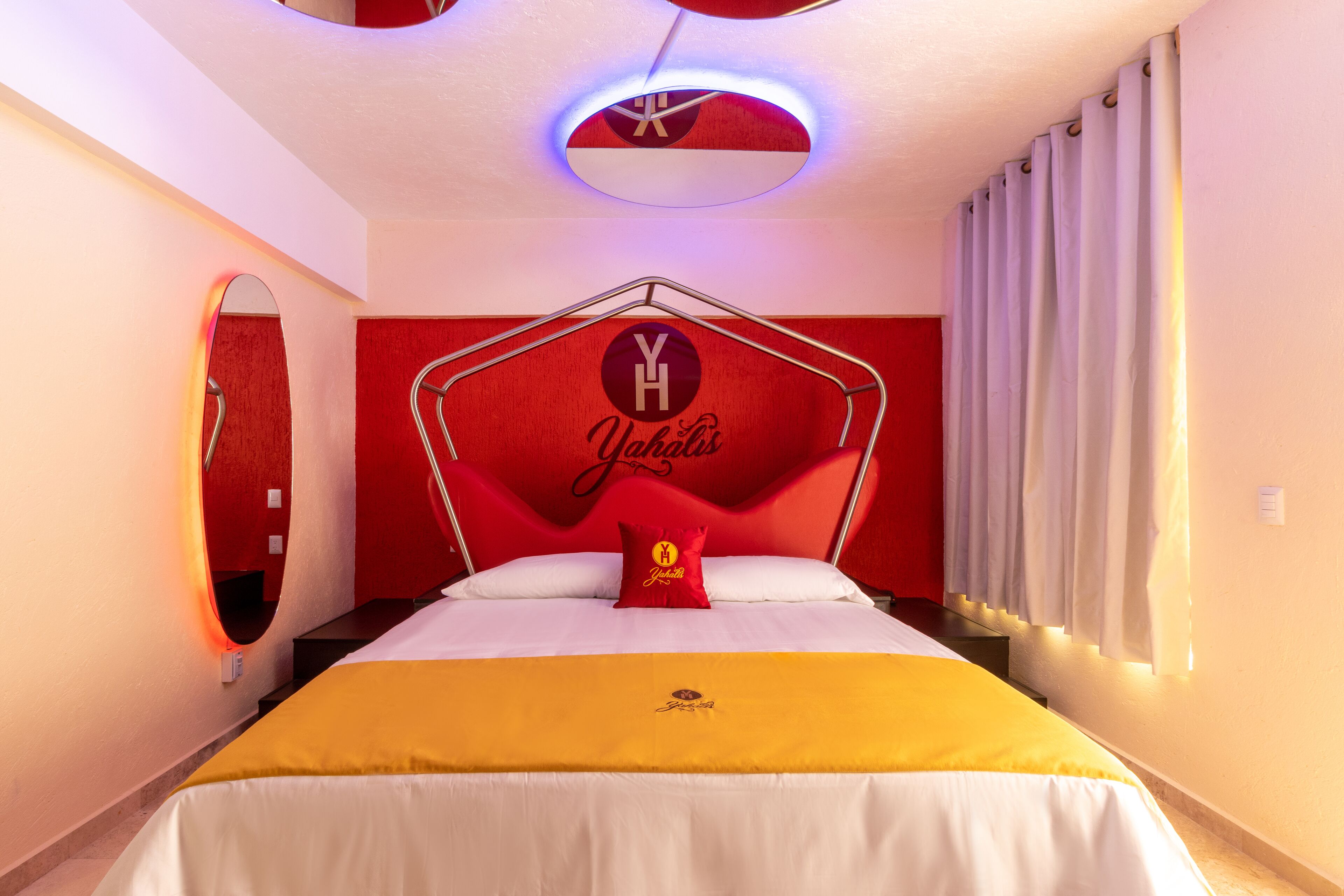 Habitación de hotel con una cama grande, una pared de acento roja y una lámpara en el techo.