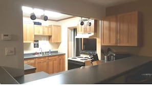 A kitchen with wooden cabinets, a stove, and a sink.