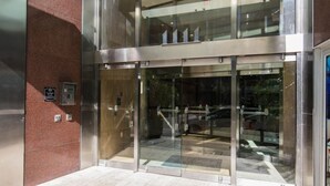 Une entrée de bâtiment moderne avec une porte en verre et un cadre métallique.