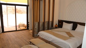 A hotel room with a large bed, a bench, and a view through a sliding door to an outdoor area. - Rum Imagination Luxury Camp (Wadi Rum)