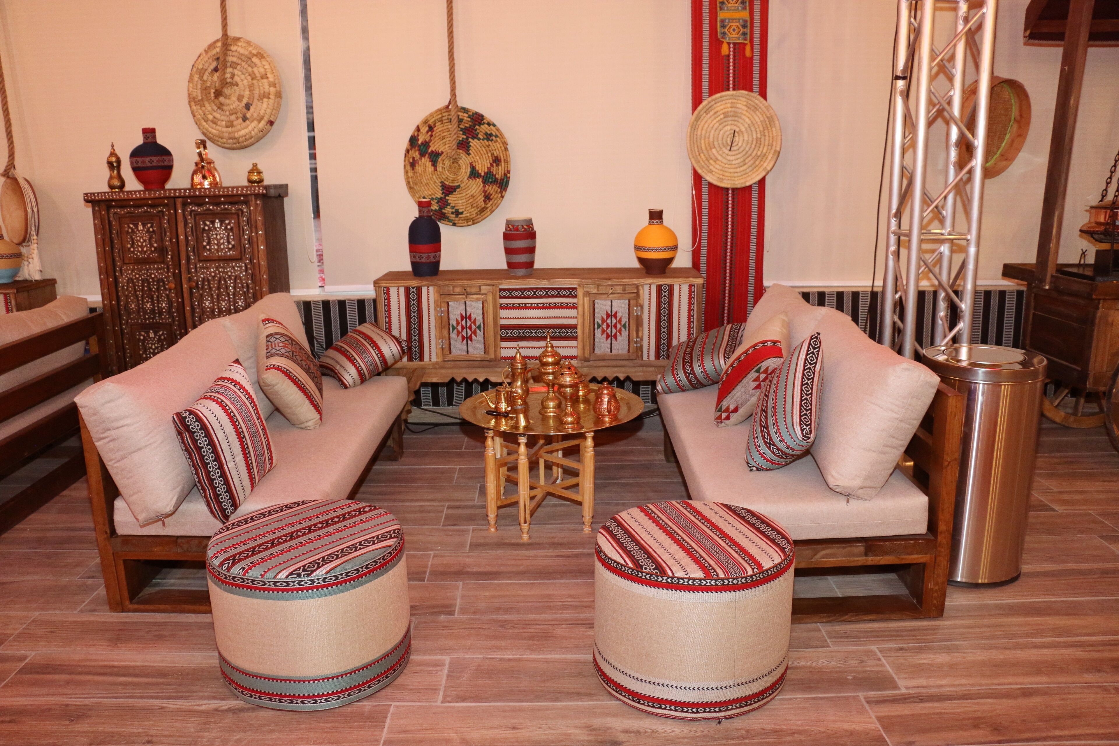 A traditional living room with a sofa set, ottomans, a coffee table, and decorative items.