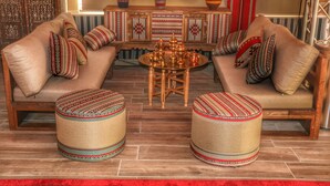 A cozy living room with two sofas, a coffee table, and two ottomans. - Rum Imagination Luxury Camp (Wadi Rum)
