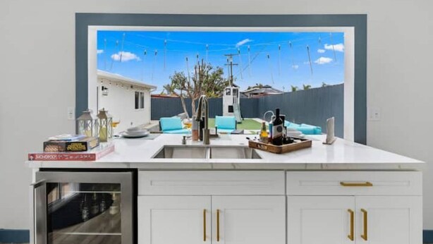 A modern kitchen with white cabinetry, a built-in oven, and a window overlooking a backyard. - Outdoor Bar/Jacuzzi/Ocean & Bay Breeze Hideaway (Chula Vista)