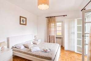 A bedroom with a bed, nightstands, a framed picture, a window with curtains, and a wardrobe. - Casa Veligato 2, San Siro, Italy (San Siro)