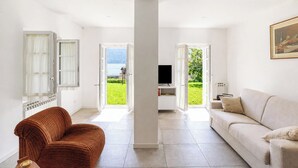 A modern living room with a sofa, a brown chair, a television, and a painting on the wall. - Casa Veligato 2, San Siro, Italy (San Siro)