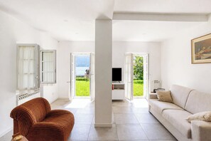 A modern living room with a sofa, a brown chair, a television, and a painting on the wall. - Casa Veligato 2, San Siro, Italy (San Siro)