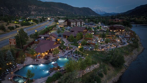 A resort with a swimming pool, multiple buildings, and a view of mountains.
