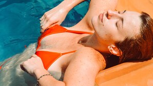 A person lying on an orange lounge chair in a swimming pool. - San PEREGRINO (Manizales)