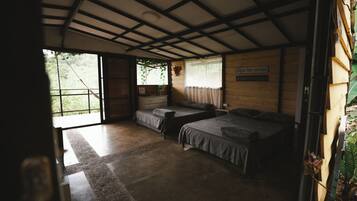 Une chambre avec deux lits, une fenêtre avec des rideaux et un plafond en bois.